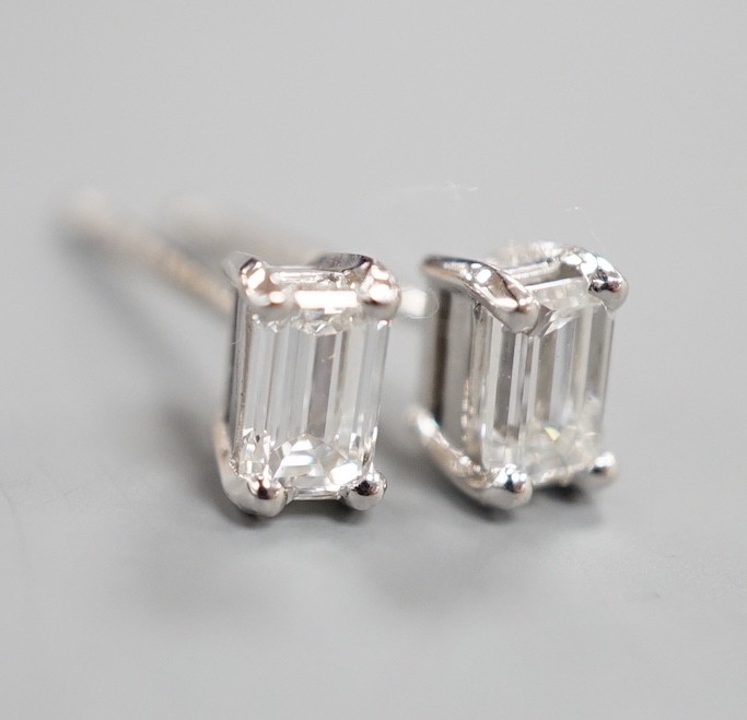 A modern pair of 750 white metal and emerald cut solitaire diamond ear studs, gross weight 1.4 grams